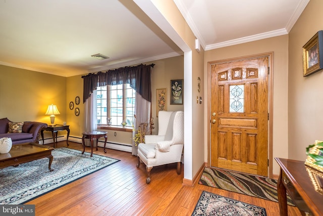 entrance foyer with a baseboard heating unit, hardwood / wood-style flooring, and ornamental molding