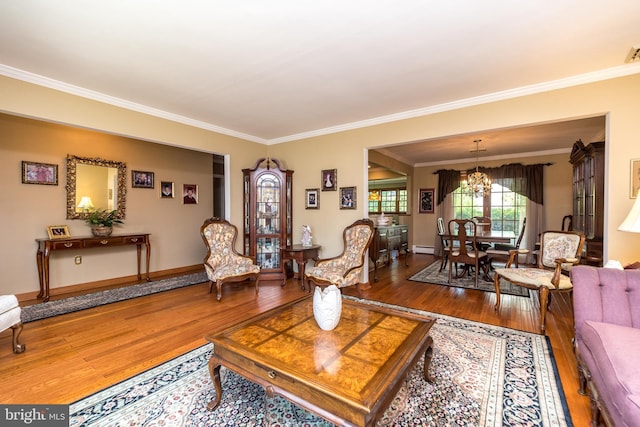 living room featuring a baseboard heating unit, hardwood / wood-style flooring, an inviting chandelier, and ornamental molding