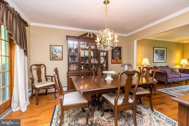 dining area with light hardwood / wood-style floors, crown molding, a wealth of natural light, and a chandelier