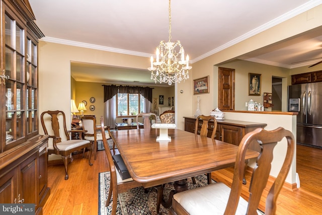 dining space featuring crown molding, light wood-type flooring, and an inviting chandelier