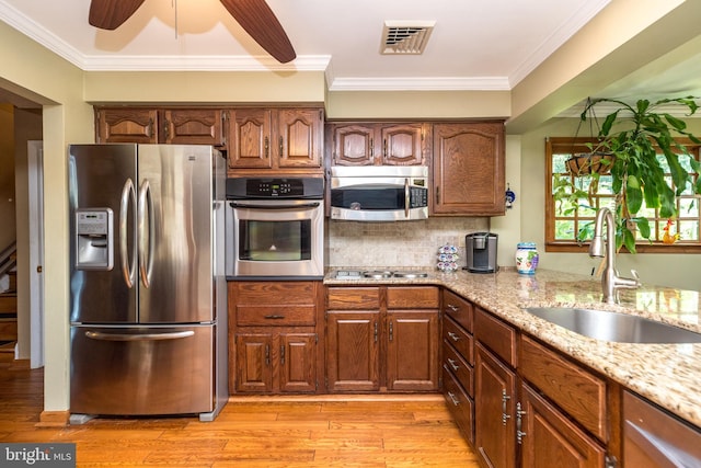 kitchen with backsplash, sink, ceiling fan, ornamental molding, and stainless steel appliances