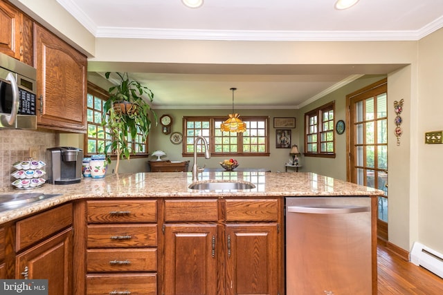 kitchen featuring sink, a baseboard radiator, decorative light fixtures, appliances with stainless steel finishes, and hardwood / wood-style flooring