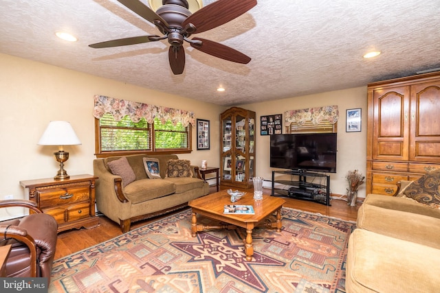 living room featuring ceiling fan, a textured ceiling, and light hardwood / wood-style flooring