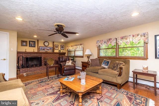 living room with ceiling fan, a baseboard radiator, a textured ceiling, and hardwood / wood-style flooring