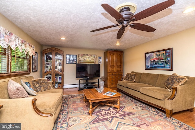 living room featuring hardwood / wood-style flooring, ceiling fan, and a textured ceiling