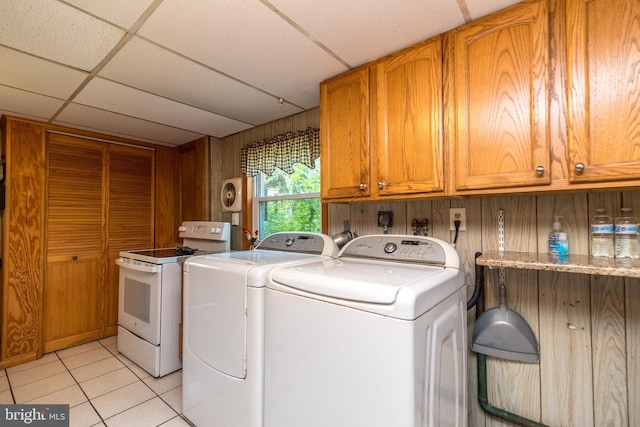 washroom with washing machine and dryer, wood walls, light tile patterned flooring, and cabinets