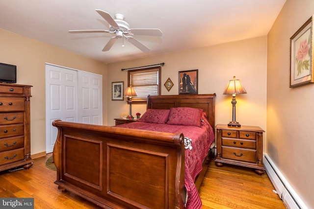 bedroom featuring ceiling fan, light wood-type flooring, baseboard heating, and a closet