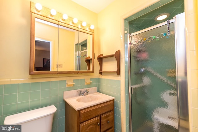 bathroom featuring vanity, toilet, an enclosed shower, and tile walls