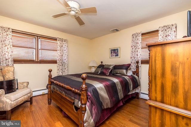 bedroom with hardwood / wood-style floors, ceiling fan, and baseboard heating