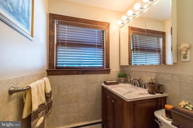 bathroom featuring vanity, toilet, and tile walls