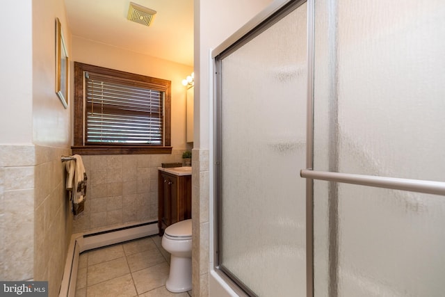 bathroom with vanity, a shower with door, tile patterned flooring, tile walls, and baseboard heating