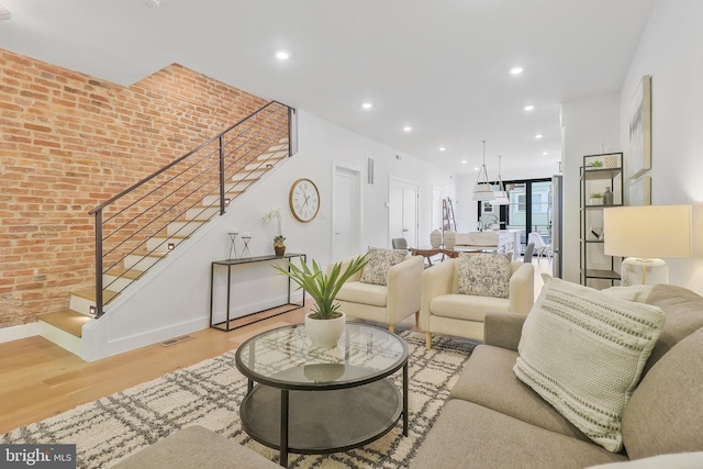 living room with brick wall and light hardwood / wood-style flooring