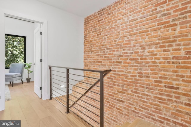 hall featuring brick wall and light hardwood / wood-style flooring