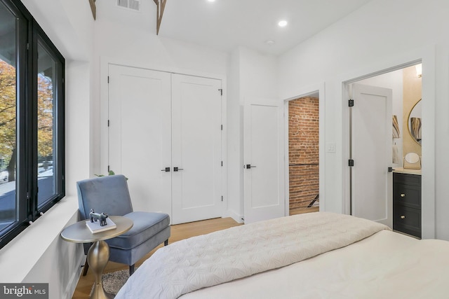 bedroom featuring a closet, ensuite bath, and light hardwood / wood-style flooring