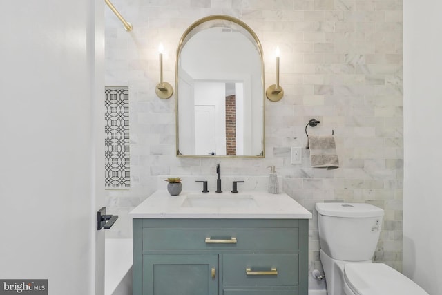 bathroom with toilet, decorative backsplash, vanity, and tile walls