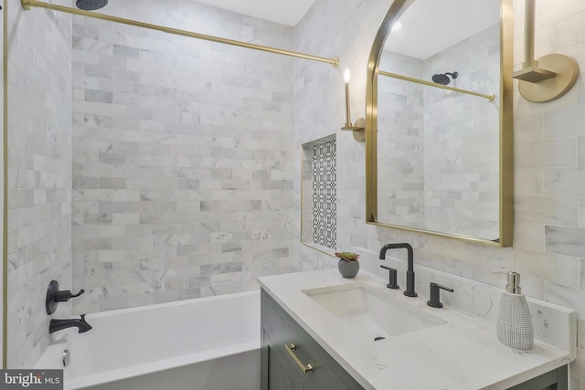 bathroom featuring vanity, tiled shower / bath, and decorative backsplash