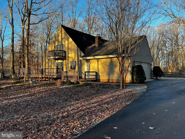 view of side of property with a balcony, a deck, and a garage