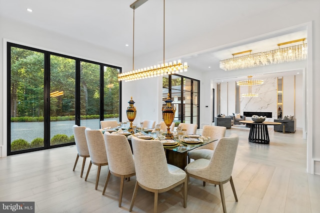 dining space with a fireplace, light hardwood / wood-style floors, plenty of natural light, and a chandelier