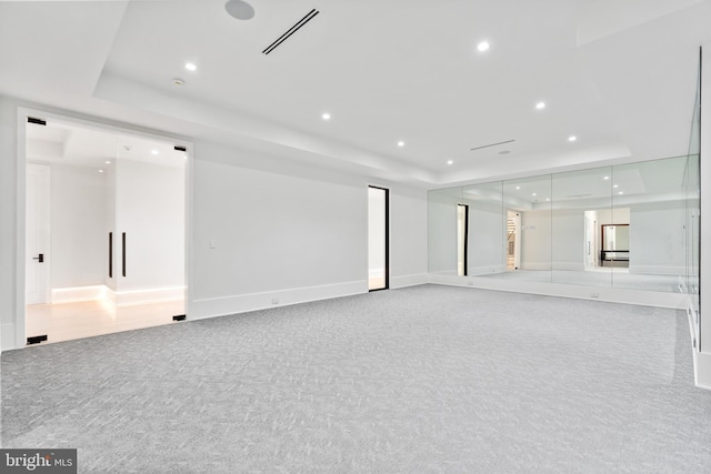 carpeted empty room featuring a tray ceiling