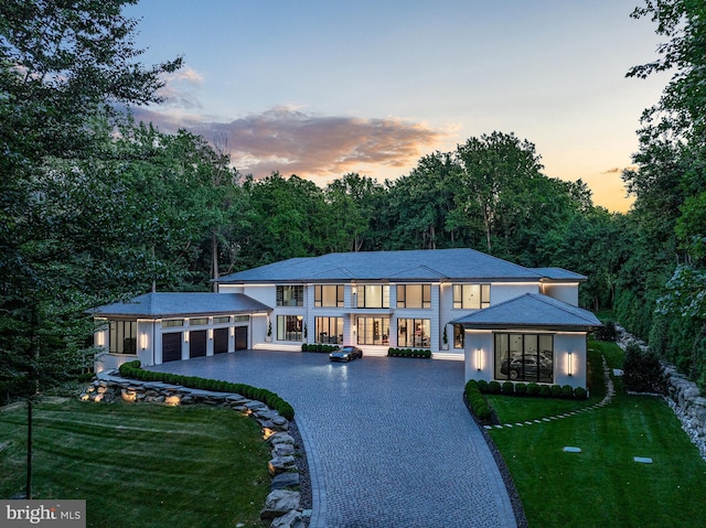 back house at dusk featuring a lawn