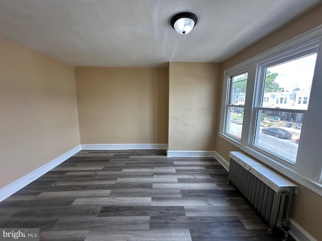 unfurnished room with radiator heating unit and dark hardwood / wood-style floors