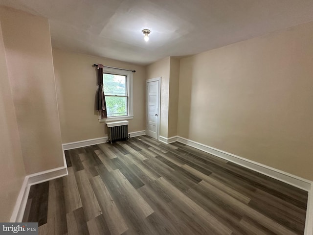 spare room featuring radiator and dark hardwood / wood-style floors