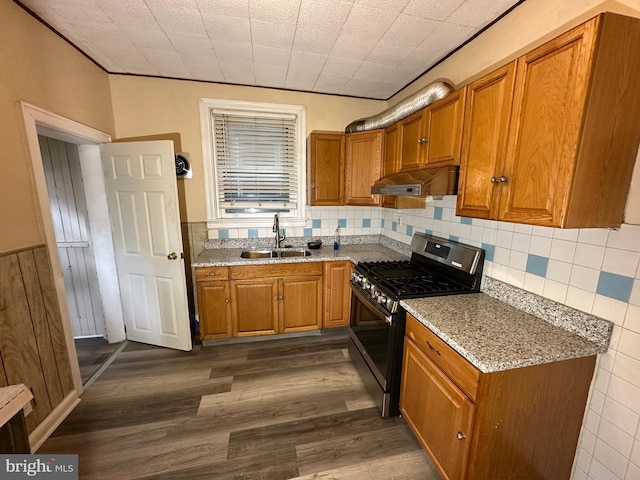 kitchen with stainless steel gas stove, sink, dark wood-type flooring, tasteful backsplash, and light stone counters