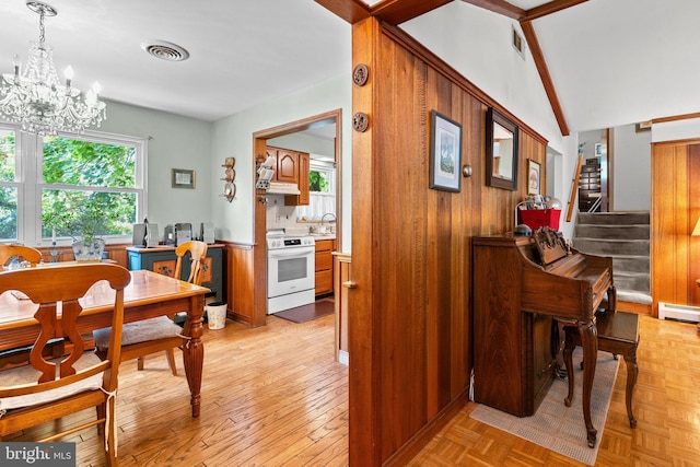 dining area with sink, a baseboard radiator, light hardwood / wood-style flooring, a notable chandelier, and wood walls