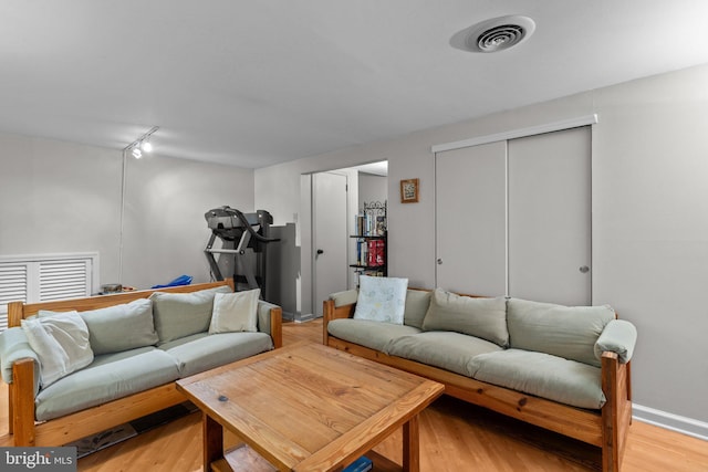 living room featuring rail lighting and light hardwood / wood-style floors