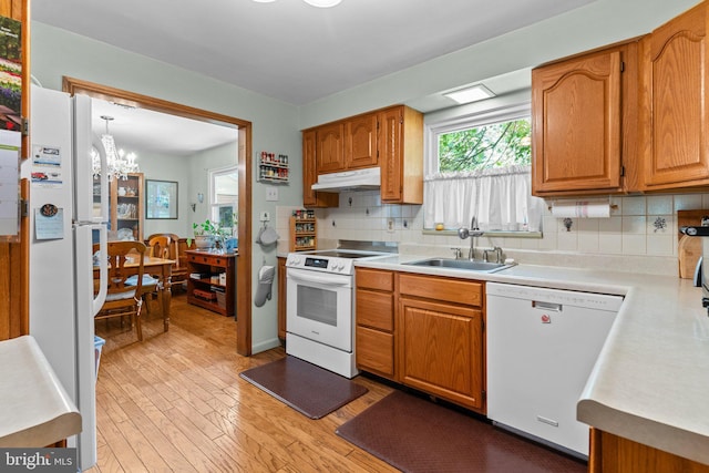 kitchen featuring sink, hanging light fixtures, backsplash, a chandelier, and white appliances