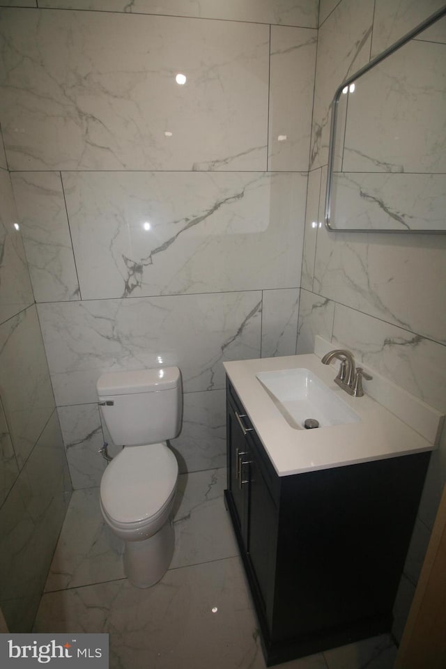 bathroom featuring vanity, toilet, and tile walls