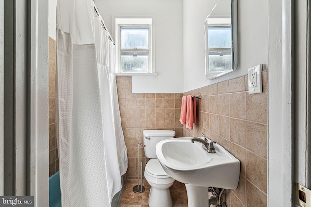 bathroom featuring toilet, tile walls, and plenty of natural light