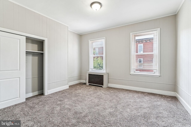 unfurnished bedroom featuring radiator heating unit, light colored carpet, multiple windows, and crown molding