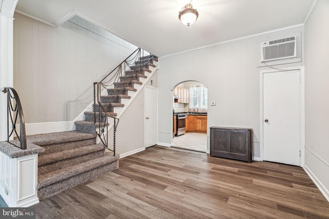 entrance foyer with a wall mounted air conditioner, ornamental molding, and hardwood / wood-style floors