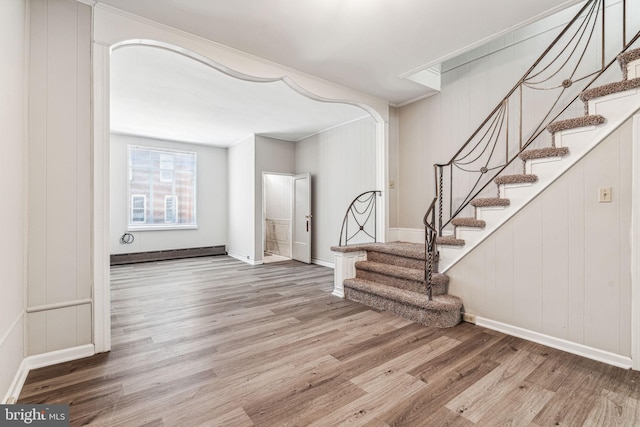 staircase with hardwood / wood-style flooring, crown molding, and a baseboard heating unit