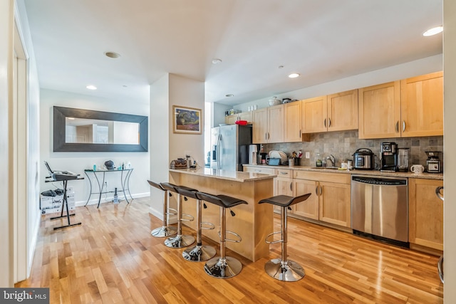 kitchen featuring sink, light wood-type flooring, light brown cabinets, a breakfast bar area, and stainless steel appliances