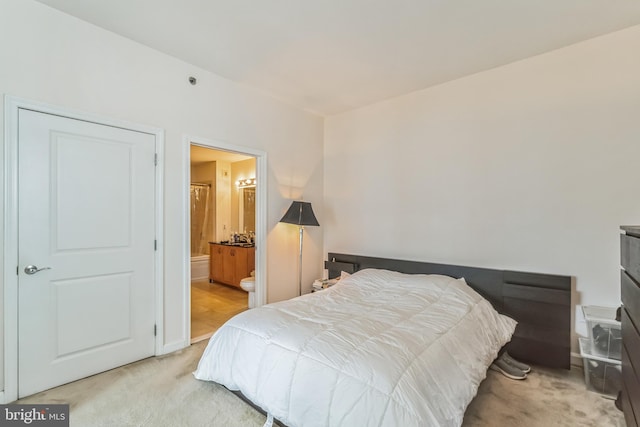 bedroom featuring connected bathroom and light carpet