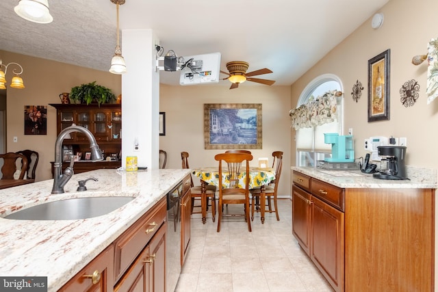 kitchen with dishwasher, sink, hanging light fixtures, ceiling fan, and light stone countertops