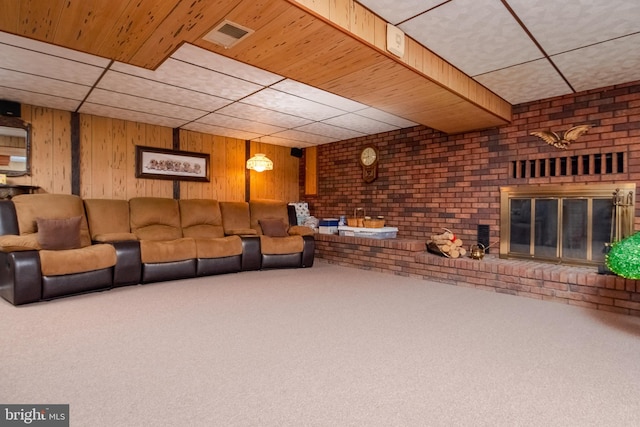 unfurnished living room with carpet, brick wall, a fireplace, and wood walls