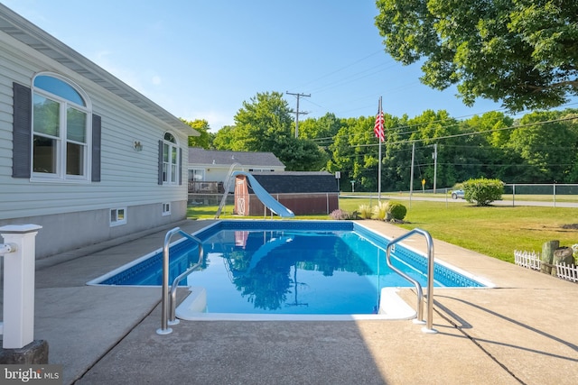 view of swimming pool with a yard, a water slide, and a patio