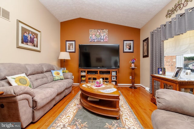 living room featuring hardwood / wood-style floors, a textured ceiling, and lofted ceiling