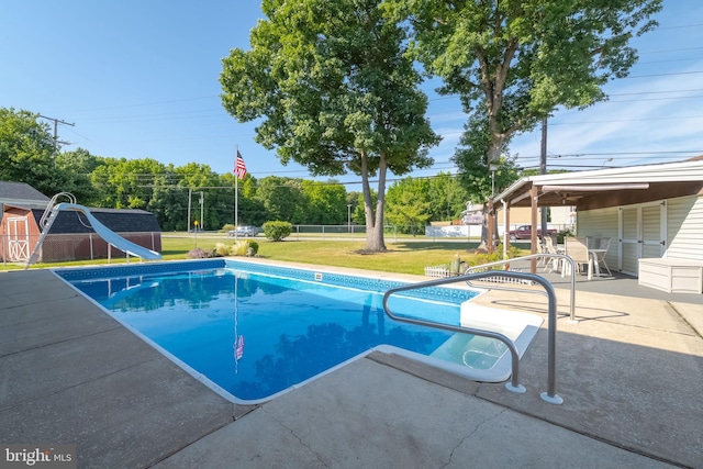 view of swimming pool featuring a patio, a lawn, and a water slide