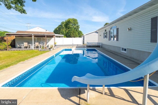 view of swimming pool with a yard, a patio area, and a water slide