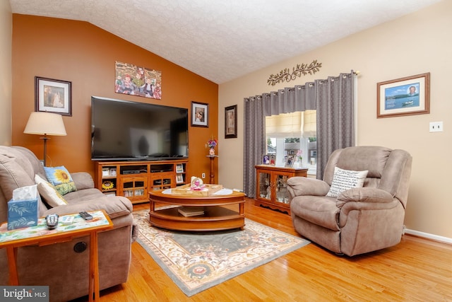 living room featuring a textured ceiling, lofted ceiling, and hardwood / wood-style flooring