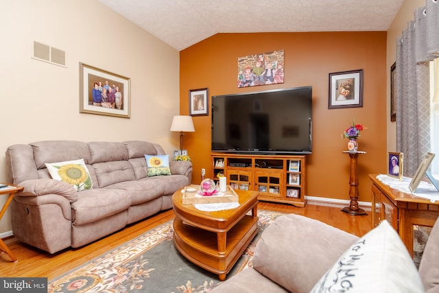 living room featuring hardwood / wood-style floors, a textured ceiling, and lofted ceiling