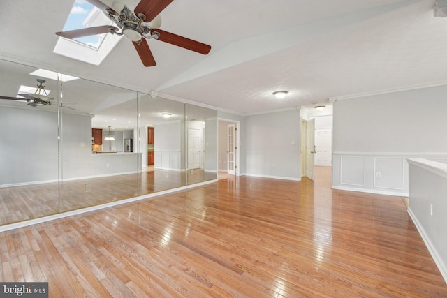 interior space with ceiling fan, ornamental molding, and light wood-type flooring