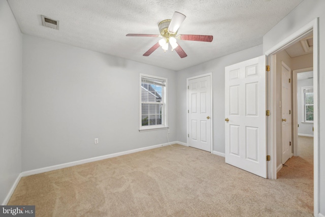 unfurnished bedroom featuring ceiling fan, light carpet, a textured ceiling, and a closet