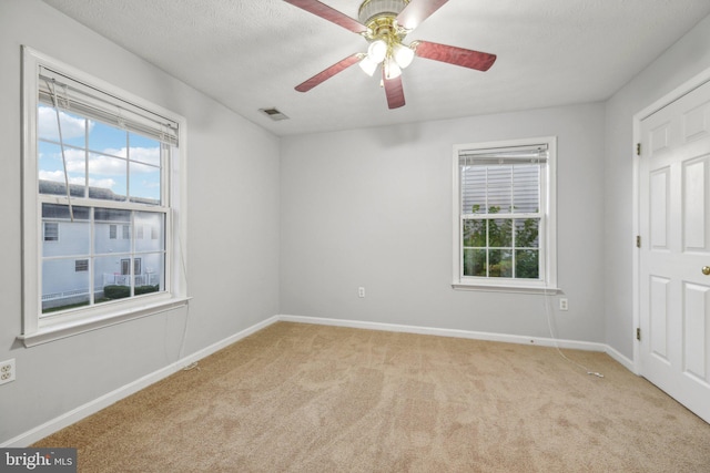 carpeted spare room featuring ceiling fan and a textured ceiling