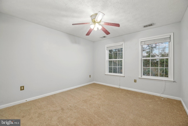 carpeted spare room featuring ceiling fan and a textured ceiling