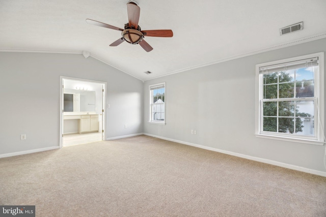 empty room featuring ceiling fan, light colored carpet, ornamental molding, and vaulted ceiling